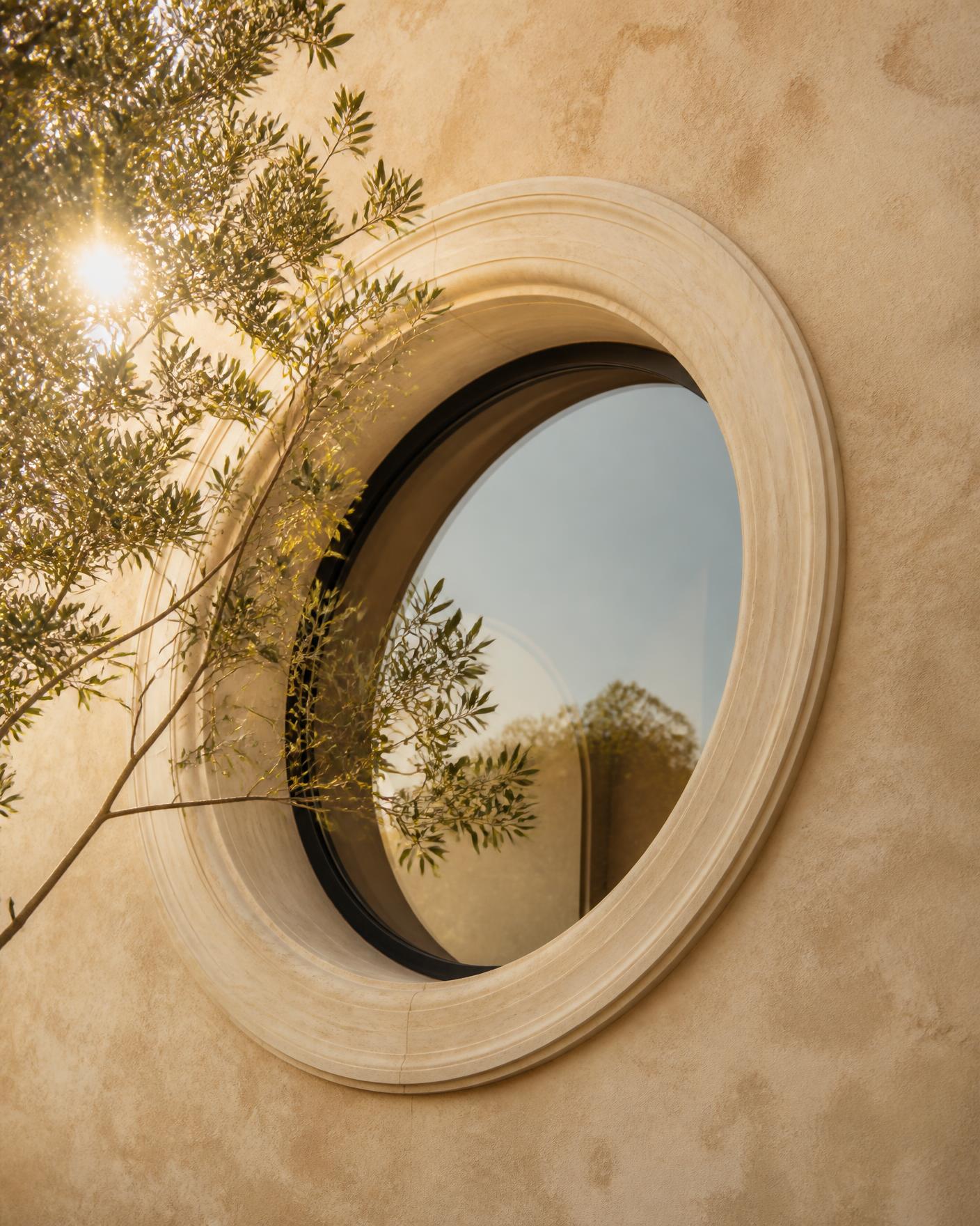 A circular stone window with an olive branch crossing the glass